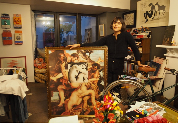 Mikele Orroño stands in her Chilean home in a Santiago suburb. She holds up a large collage that combines a cutout image from a magazine and a reproduction of a painting.   