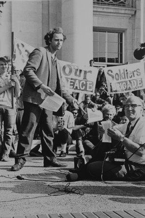 Mario Savio on UC Berkeley’s campus in 1966. Here, he is deliberately defying campus regulations by handing out political material to others. Photo from WikiMedia Commons. 