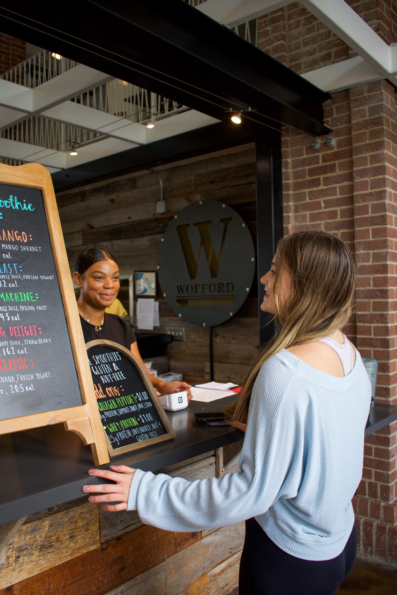 Caris Mitchell ‘27 serves a student during the soft launch of Studio Smoothie. Mitchell’s entrepreneurship is expanding fresh fruit options on Wofford’s campus.
